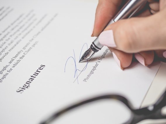 hand holding a fountain pen to sign a contract on the signature line