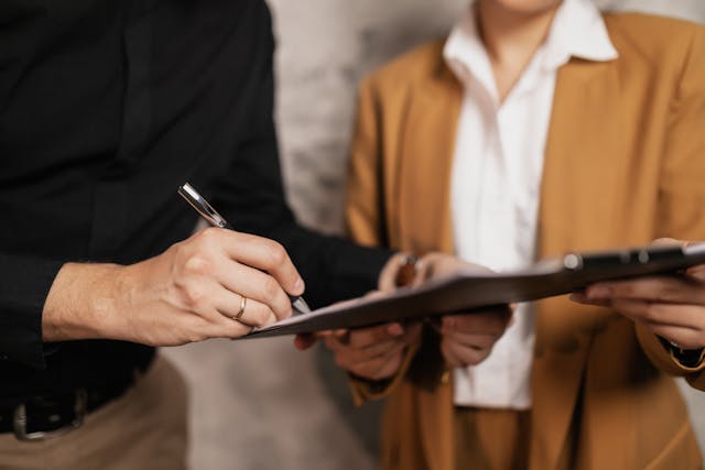 A person signing a document on a clipboard