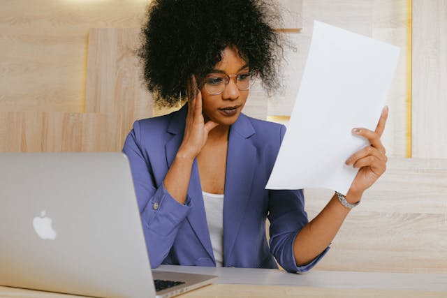 a person in a blue blazer reviewing a document at their desk